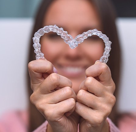 Hands holding Invisalign in the shape of a heart