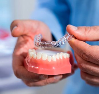 Dentist placing Invisalign over sample teeth