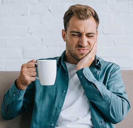 Man in pain holding cheek before emergency dentistry