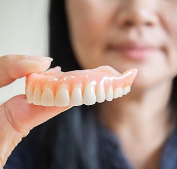 A closeup of a removable denture held by a hand