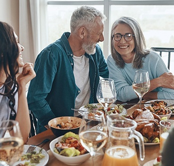 older couple smiling and laughing while eating dinner 