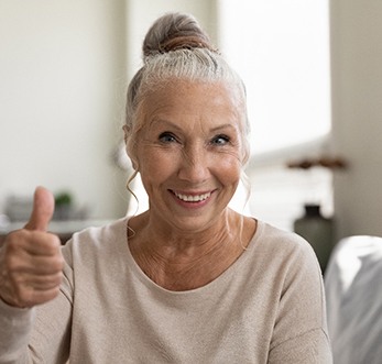 woman smiling while giving thumbs up 