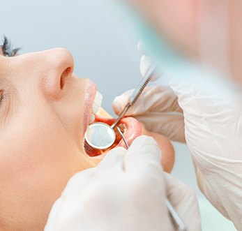 dentist looking at patient’s mouth 