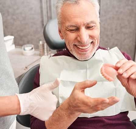 Patient holding dentures and talking to their dentist