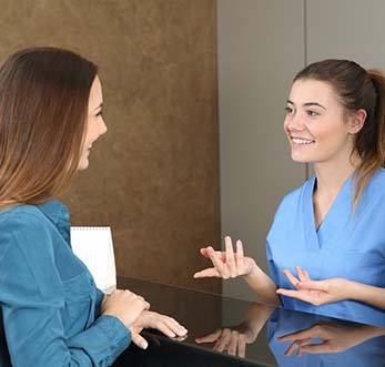 Receptionist and patient discussing how to make dental emergencies affordable in Mt. Pleasant