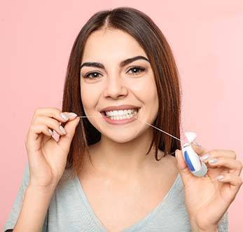 Woman flossing to prevent dental emergencies in Mt. Pleasant