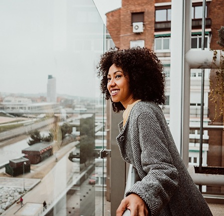 Person smiling and looking out from a balcony after tooth extraction