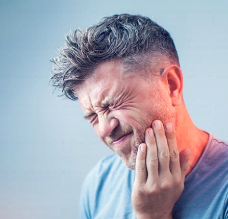 Man with mouth pain, experiencing symptoms of a failed dental implant