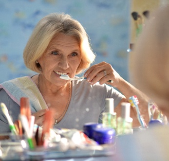 Woman brushing her teeth after dental implant surgery in Mt. Pleasant