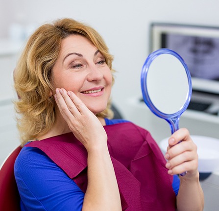 woman looking her smile in a mirror