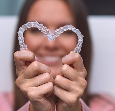 Woman forming heart shape with Invisalign trays in Mt. Pleasant