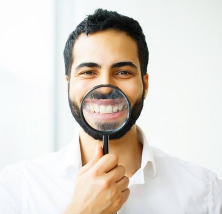 man in white dress shirt holding magnifying glass to his smile