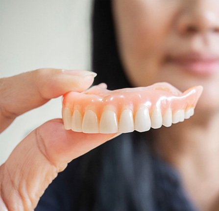 Woman holding dentures