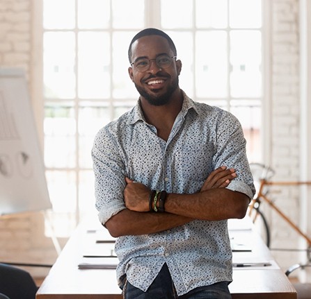 Person smiling and sitting with their arms crossed after root canal therapy