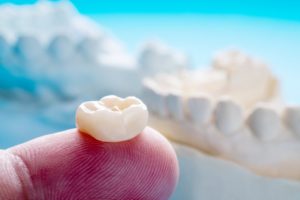 person holding dental crown on their finger 