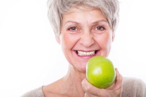 Woman with dental implants holding an apple