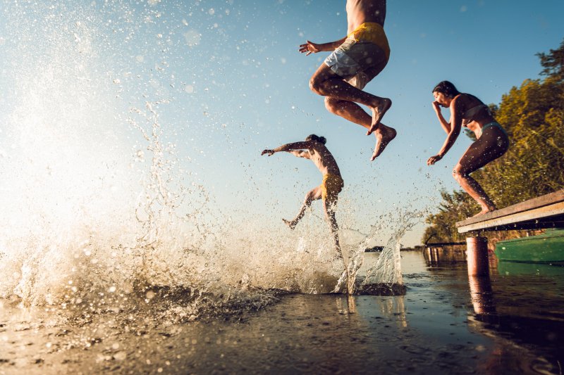 A group of summer vacationers jumping into a lake
