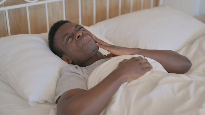 man lying in bed with a toothache